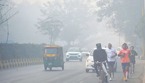 People walk amid smog near Bharat Mandapam on Sunday morning