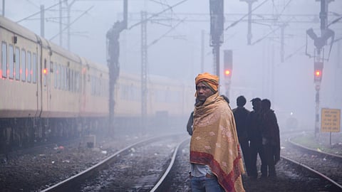 A man covers himself with warm clothes on a winter morning, in Kanpur, Sunday, Dec. 28, 2025.