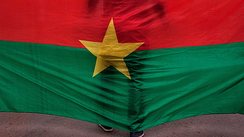 The Burkina Faso national flag with a man standing in front of it is seen during a memorial ceremony in Ouagadougou, Burkina Faso, Jan. 23, 2016.