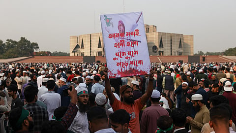 A Bangladeshi mourner holds a poster bearing the portrait of deceased youth leader Sharif Osman Hadi during his funeral in Dhaka on December 20, 2025.
