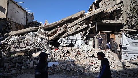 Palestinians walk past the debris of a collapsed house in the Gaza Strip.
