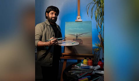 Purnama Chary Kagithala poses with one of his paintings, Dream of Paradisi