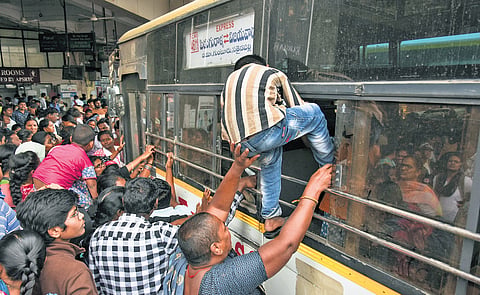A youngster boards an APSRTC bus through a window at the crowded Pandit Nehru Bus Station in Vijayawada on Sunday.