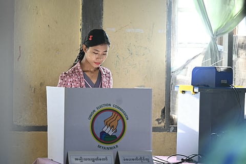 A woman casts her vote at a polling station during the second phase of Myanmar's general election at Kawhmu township in Yangon on January 11, 2026.