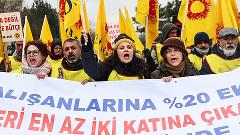 Protesters chant slogans and hold placards and banners reading "20% extra increase now!"