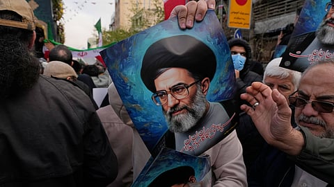 A man hands out posters of the Iranian Supreme Leader Ayatollah Ali Khamenei during a funeral ceremony for a group of security forces, who were killed during anti-government protests, in Tehran, Iran, Wednesday, Jan. 14, 2026.