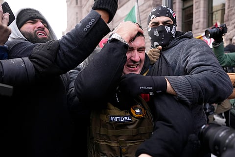 Jake Lang, center, who organized the protest March Against Minnesota Fraud, clutches his head as he leaves the rally near Minneapolis City Hall, Saturday, Jan. 17, 2026, in Minneapolis.