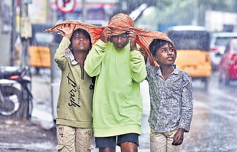 Children covering their heads with a piece of cloth as intermittent rain hit parts of Chennai on Saturday