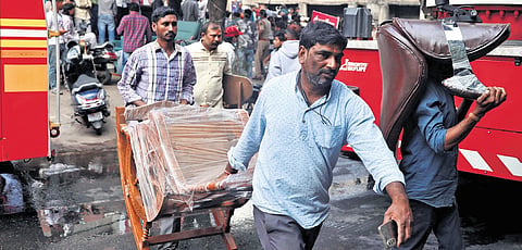 Store staff shift furniture items from the affected shop in Nampally,
Hyderabad, on Saturday.