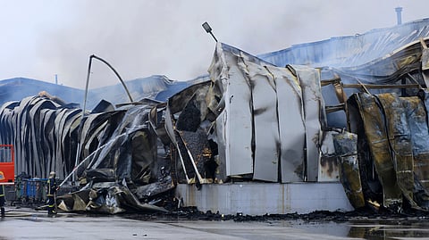 A firefighter sprays water after an explosion and fire at a cookie factory in Trikala, central Greece, on Monday, Jan. 26, 2026.