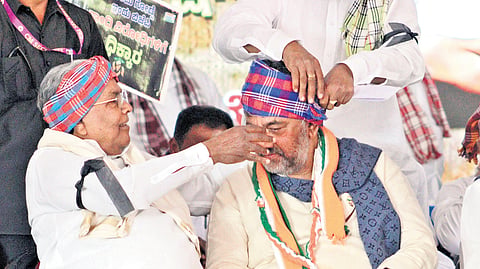 Chief Minister Siddaramaiah helps Deputy CM DK Shivakumar tie a turban during
a protest against the Centre’s move to replace MGNREGA with VB-G RAM G, at Freedom Park in Bengaluru on Tuesday