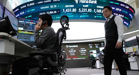 A currency trader talks on the phone near a screen showing the Korea Composite Stock Price Index (KOSPI), top center, and the foreign exchange rate between U.S. dollar and South Korean won, top center left, at the foreign exchange dealing room of the Hana Bank headquarters in Seoul, South Korea, Friday, Jan. 30, 2026.