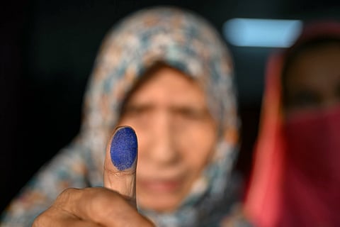 A voter holds up her inked finger after casting her vote at a polling station during Bangladesh's general election in Dhaka on February 12, 2026.