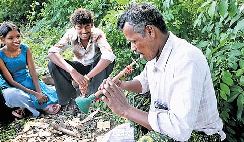 Sreekrishnan, one of the few remaining makers of the kokkal instrument in Bhoothivazhi village in Agali, playing the wind instrument as his mentees watch on