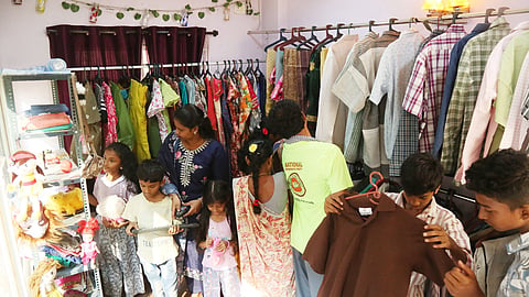 A few people, including children, search through the shelves at Free Shop Vizag to pick clothes and toys they need