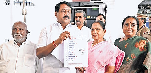 BJP state president Nainar Nagenthran posing with the report card outside the Assembly.