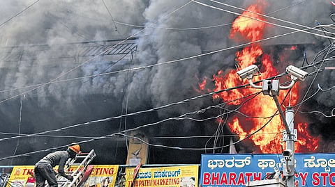 Fire and Emergency Services personnel douse the fire at a 40-year-old commercial complex near Chickpet Metro Station on Wednesday