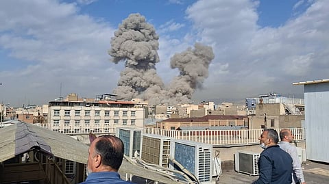 People watch as smoke rises on the skyline after an explosion in Tehran, Iran, Saturday, Feb. 28, 2026.