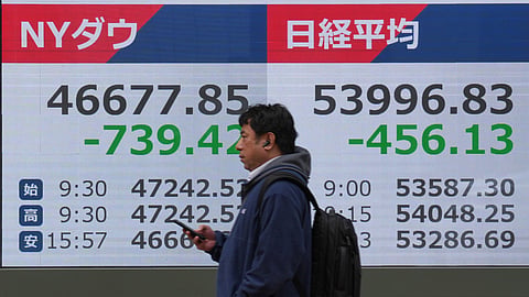 A person walks in front of an electronic stock board showing Japan's Nikkei index at a securities firm Friday, March 13, 2026, in Tokyo.
