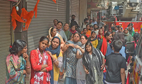Neighbours and public watch as rescue operations are underway after a fire broke out in a residential building near Palam Metro station, in New Delhi, Wednesday, March 18, 2026.