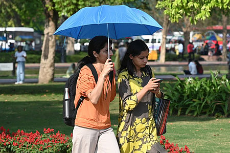 People seen covering their head with umbrella to protect themselves from heat on a summer day at kartavya Path in New Delhi on Tuesday.