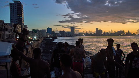 People watch the sunset from the Malecón during a blackout in Havana, Monday, March 16, 2026.