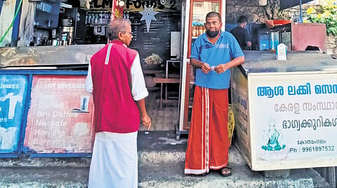 Tea stall owner Jagadish discussing politics, development with a lottery vendor near Kothamangalam
