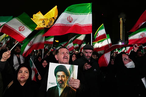 Pro-government supporters wave national flags as one of them holds a picture of the Supreme Leader Ayatollah Mojtaba Khamenei during a rally in a square in western Tehran, Iran, Wednesday, March 25, 2026.