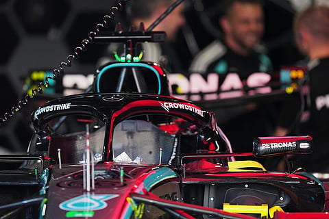 Mercedes driver George Russell of Britain's car is seen in the garage as mechanics talk nearby in Suzuka, central Japan.