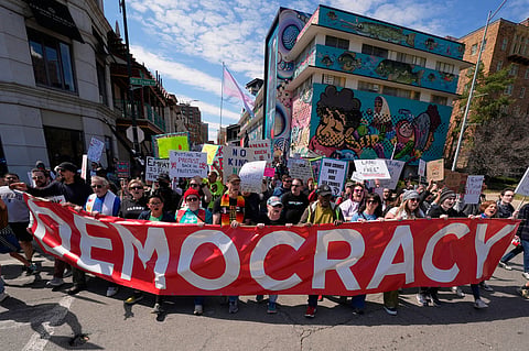 Demonstrators march through the Country Club Plaza shopping district during a "No Kings" protest Saturday, March 28, 2026, in Kansas City, Mo.