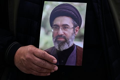 A man holds a poster of the Iranian Supreme Leader Ayatollah Mojtaba Khamenei during the funeral procession of Gen. Ali Mohammad Naeini, a spokesperson for Iran’s paramilitary Revolutionary Guard and one of his comrades Amir Hossein Bidi in Tehran, Iran, Saturday, March 21, 2026.