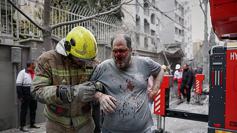 A first responder assists an injured man following a strike that hit a residential building amid the US-Israeli military campaign in Tehran, Iran, on Saturday, March 28, 2026.