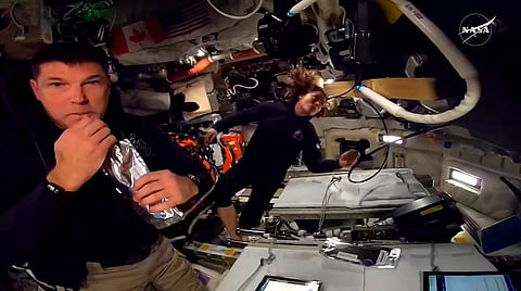 This screengrab from a NASA live broadcast video footage shows NASA astronaut and Artemis II Mission Specialist Christina Koch (R) and Canadian Space Agency astronaut Artemis II Mission Specialist Jeremy Hansen working inside the Orion spacecraft