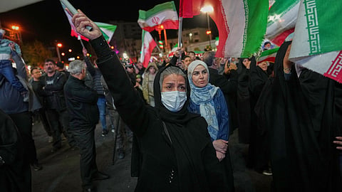 Women hold Iranian flags during a pro-government gathering in a square in Tehran, Iran, Sunday, April 5, 2026.