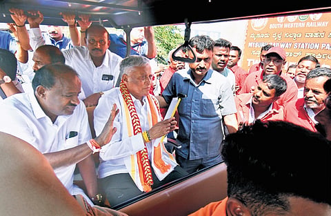 Porters working at Mysuru railway station handover a memorandum to MoS for Railways V Somanna and Union Minister H D Kumaraswamy in Mysuru on Thursday