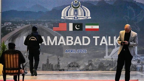 A security guard walks past a billboard outside a media centre set up for the coverage of the US-Iran official meeting in Islamabad, Pakistan, Sunday, April 12, 2026.