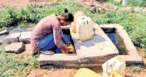 A woman fetches water from an air valve sump of a municipal pipeline at Ramannapally Colony in Jammikunta of Karimnagar district