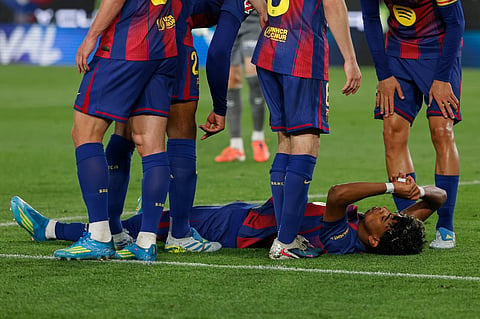 Barcelona's Lamine Yamal lies on the pitch in pain during the Spanish La Liga soccer match between Barcelona and Celta Vigo in Barcelona, Spain, Wednesday, April 22, 2026.