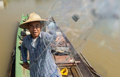 Fisherman Sukjai Yana untangles his net while docked on the Kok River in Chiang Saen, Thailand, on Feb. 17, 2026.