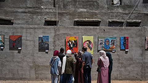 People look at paintings by Palestinian artists during an exhibition in Al-Bureij camp in the central Gaza Strip Tuesday, April 28, 2026.