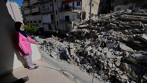 Em Ali Khodor, 75, looks through her damaged apartment into a destroyed building that was hit few weeks ago by an Israeli airstrikeafter she returns to the house, in the southern port city of Tyre, Lebanon, Thursday, April 30, 2026.