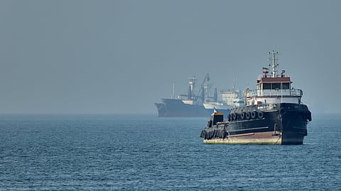 An Iranian tugboat floats in the foreground as cargo ships sit at anchor in the Strait of Hormuz off Bandar Abbas, Iran, Monday, May 4, 2026.