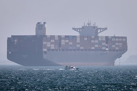 A container ship sits at anchor as a small motorboat passes in the foreground in the Strait of Hormuz off Bandar Abbas, Iran, Saturday, May 2, 2026.