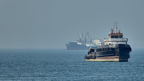An Iranian tugboat floats in the foreground as cargo ships sit at anchor in the Strait of Hormuz off Bandar Abbas, Iran, Monday, May 4, 2026.
