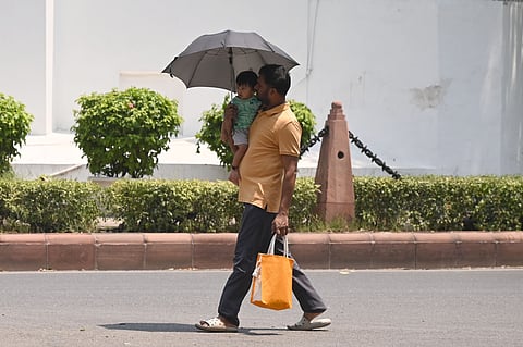 People are seen protecting themselves from the sun on a summer day on May 02, 2026 in New Delhi.