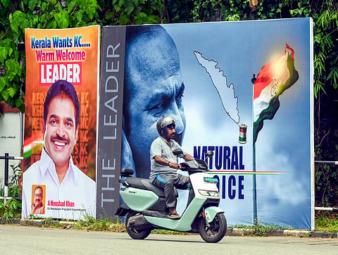 A man rides past posters supporting KC Venugopal and VD Satheesan near the Congress headquarters, in Thiruvananthapuram, Friday, May 8, 2026.