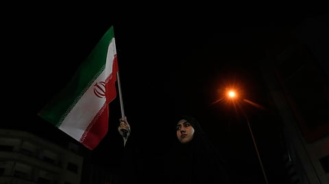 A woman holds up an Iranian flag for a pro-government campaign in downtown Tehran, Iran, Friday, May 8, 2026.