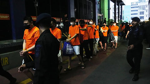 Indonesian police officers escort foreign nationals in a raid on an alleged online gambling operation in Jakarta, Indonesia, Sunday, May 10, 2026.