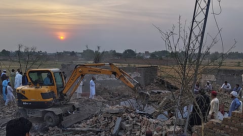 A worker clear rubble with an excavator as a police officers and local residents gather at the site of overnight suicide bombing at a security post in Fatah Khel, in Bannu, a district in Pakistan's Khyber Pakhtunkhwa province bordering Afghanistan, Sunday, May 10, 2026.