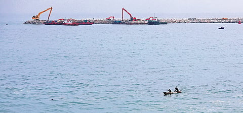 A fisherman rows through the waters off Vizhinjam port as the Phase-II construction work progresses at a rapid pace in the background.